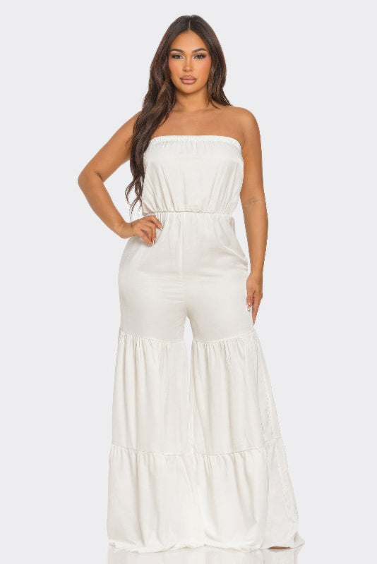 Woman wearing a white strapless jumpsuit on a plain background