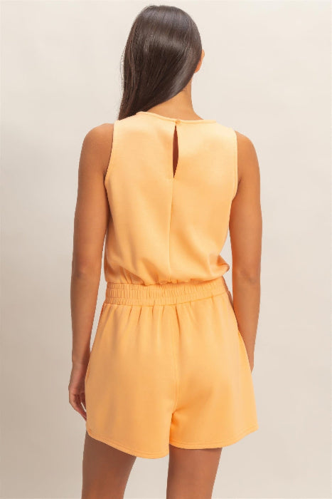Woman wearing a yellow romper against a neutral background