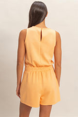 Woman wearing a yellow romper against a neutral background