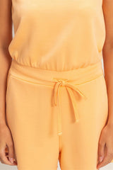 Person wearing a yellow sleeveless romper on a light gray background