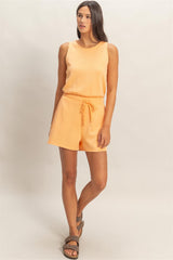 Woman wearing a peach-colored Drawstring Waist Sleeveless Romper on a plain background