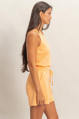 Woman wearing a yellow romper against a plain background